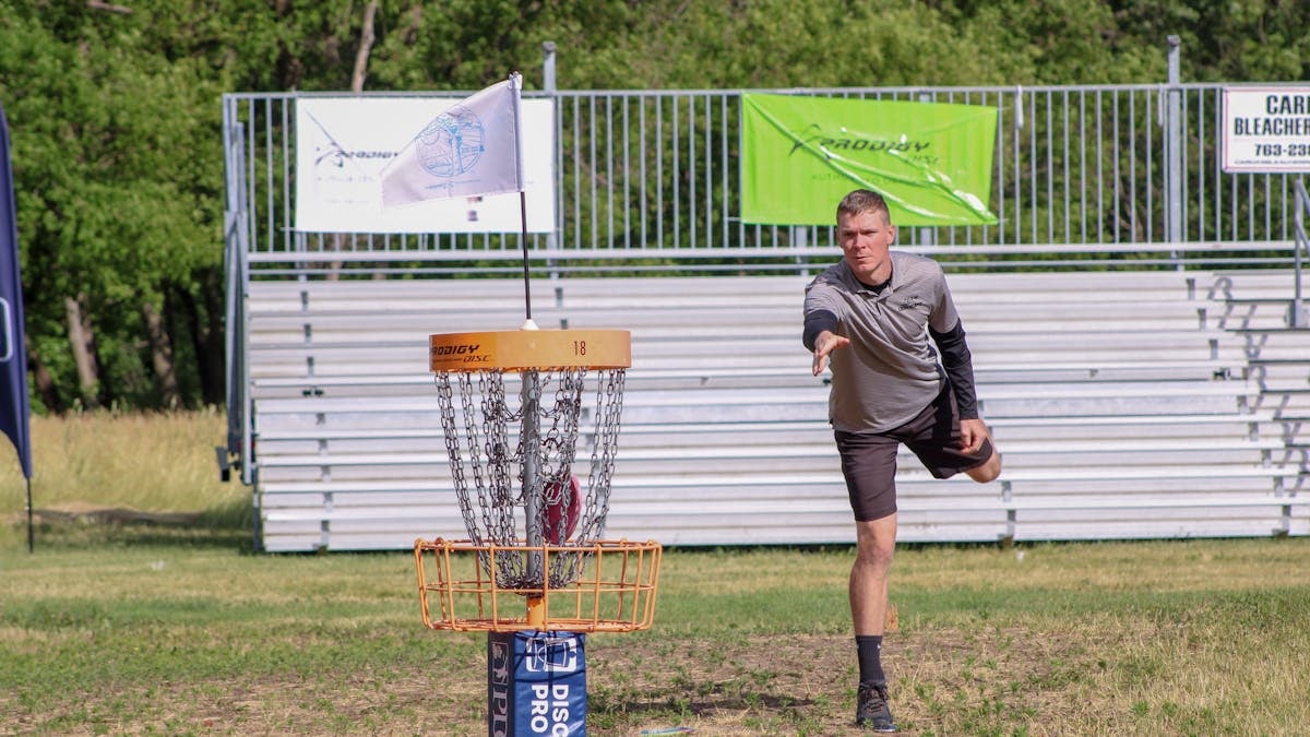 A man throws a disc towards the basket during a disc golf tournament in Clearwater, MN.